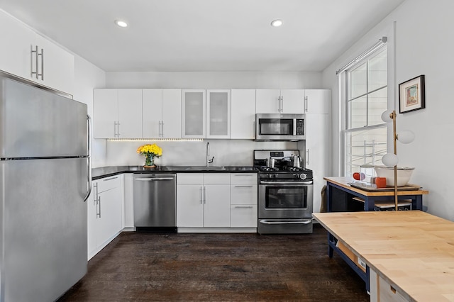 kitchen featuring stainless steel appliances, dark wood finished floors, white cabinetry, and glass insert cabinets