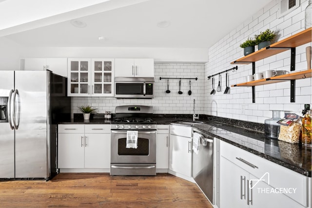 kitchen featuring a sink, open shelves, tasteful backsplash, stainless steel appliances, and dark wood-style flooring