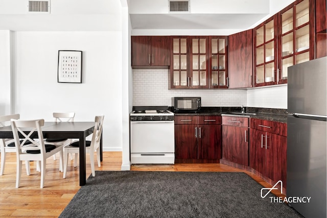 146 W 136th St, New York City, NY 10030 - kitchen featuring freestanding refrigerator, white gas range oven, black microwave, dark brown cabinets, and dark countertops