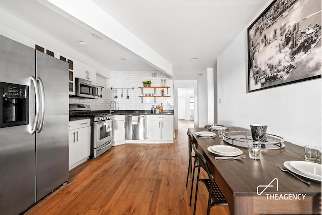 kitchen with white cabinetry, open shelves, dark countertops, and stainless steel appliances