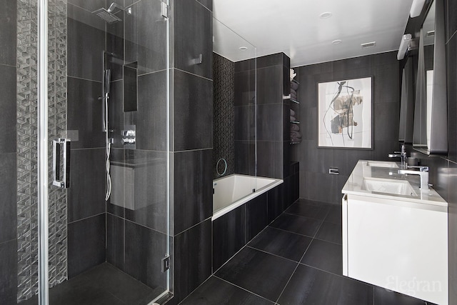 bathroom with a sink, tile patterned flooring, a shower stall, a garden tub, and tile walls