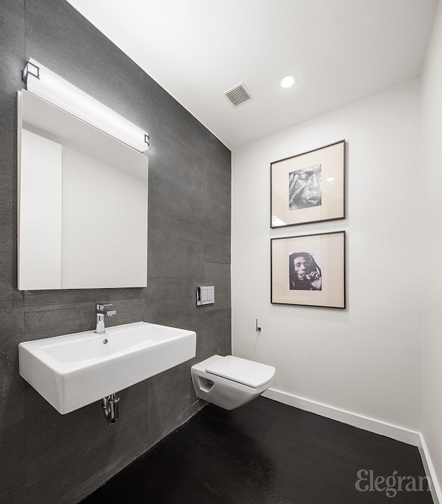 bathroom with visible vents, toilet, a sink, wood finished floors, and baseboards