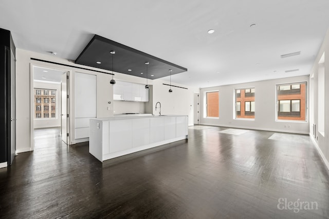 unfurnished living room with visible vents, dark wood-style floors, baseboards, and a sink