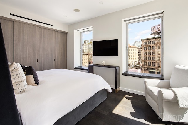 bedroom with dark wood finished floors, multiple windows, and baseboards