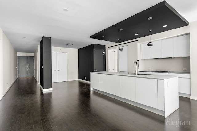 kitchen featuring dark wood-style floors, black cooktop, a sink, white cabinetry, and modern cabinets