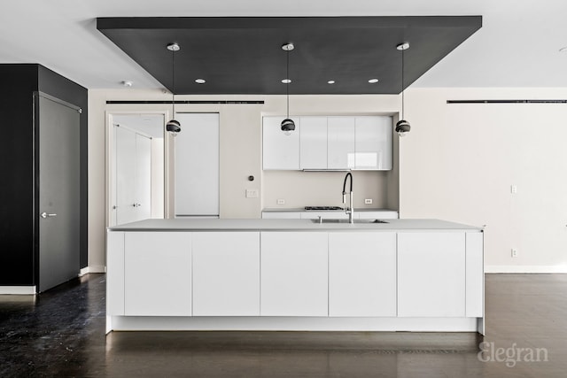 kitchen with modern cabinets, a sink, white cabinetry, light countertops, and hanging light fixtures