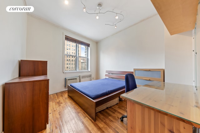 bedroom featuring visible vents, radiator, a wall mounted AC, and light wood finished floors