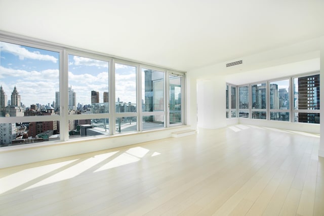 spare room featuring a city view, wood finished floors, and visible vents