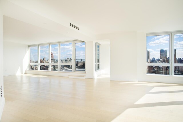 empty room with visible vents, a view of city, and wood finished floors