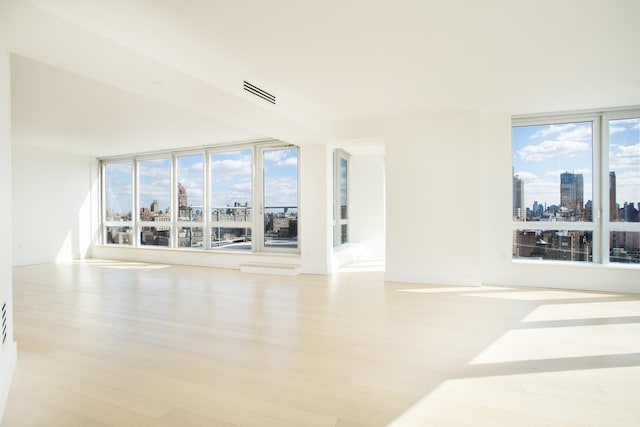 unfurnished room with visible vents, a view of city, and wood finished floors