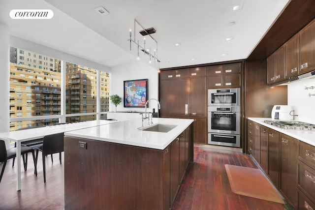 151 E 85th St Unit 15J, New York City, NY 10028 - kitchen with a sink, stainless steel gas cooktop, light countertops, dark wood-style floors, and glass insert cabinets