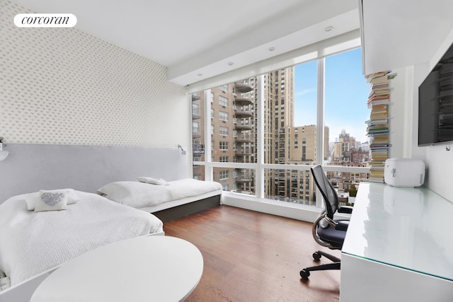 office space with wallpapered walls, wood finished floors, and expansive windows