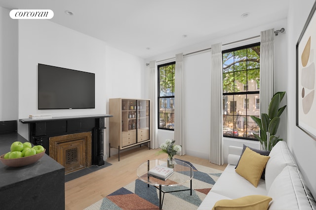 living area with a fireplace with flush hearth, plenty of natural light, visible vents, and light wood-style floors