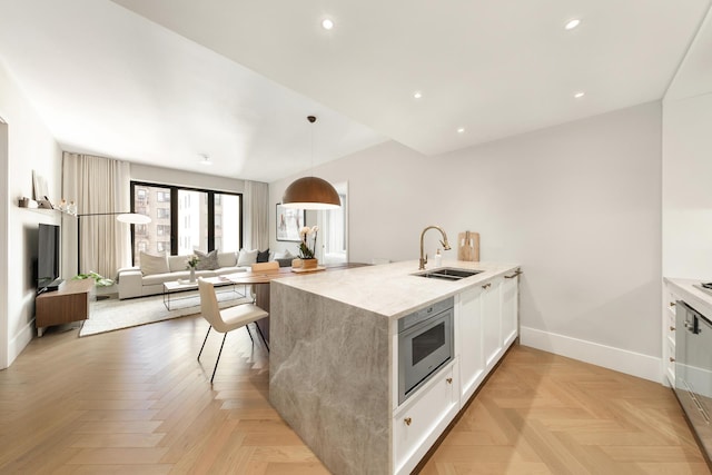 kitchen with baseboards, a peninsula, a sink, white cabinets, and open floor plan