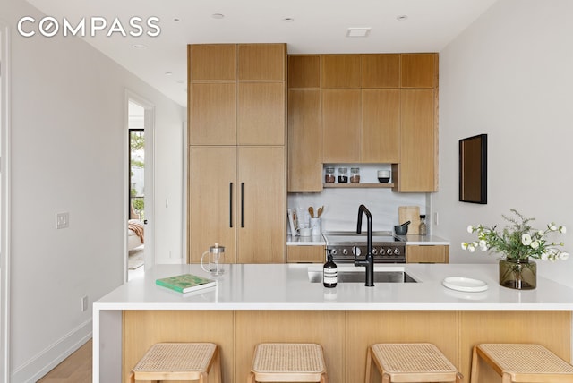 kitchen featuring light countertops, a kitchen breakfast bar, modern cabinets, and a sink