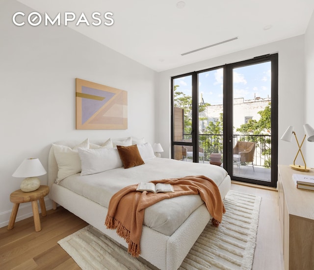 bedroom with access to exterior, light wood-style floors, and baseboards