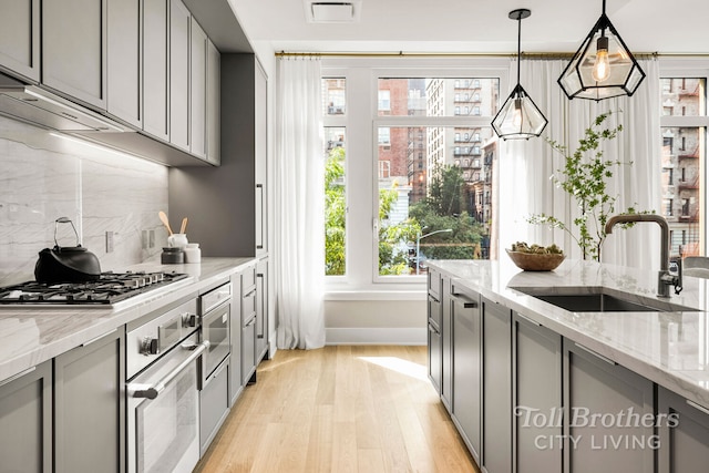 kitchen with visible vents, gray cabinets, light wood-style floors, stainless steel appliances, and a sink