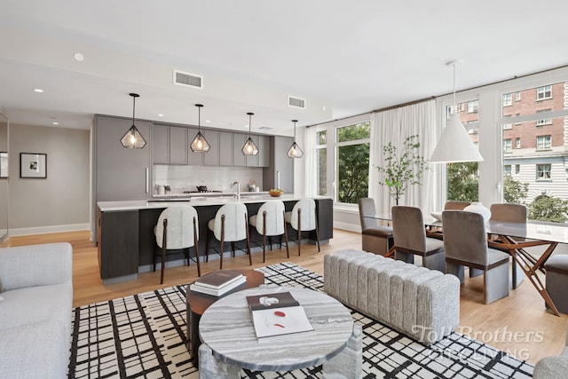 living area with recessed lighting, visible vents, light wood-style flooring, and baseboards