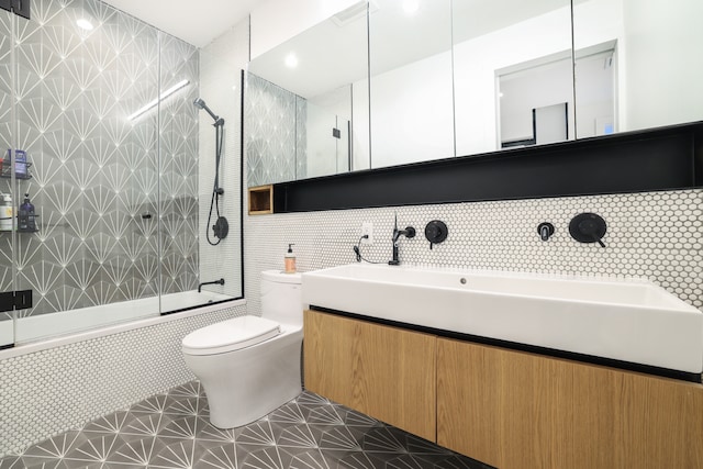 bathroom featuring vanity, toilet, tile walls, and tiled shower / bath