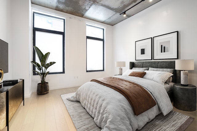 bedroom with baseboards, wood finished floors, and rail lighting