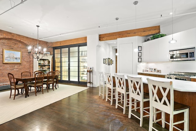 dining room featuring an inviting chandelier, brick wall, and dark wood finished floors