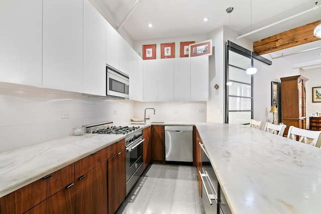 kitchen with modern cabinets, light stone counters, tasteful backsplash, and appliances with stainless steel finishes