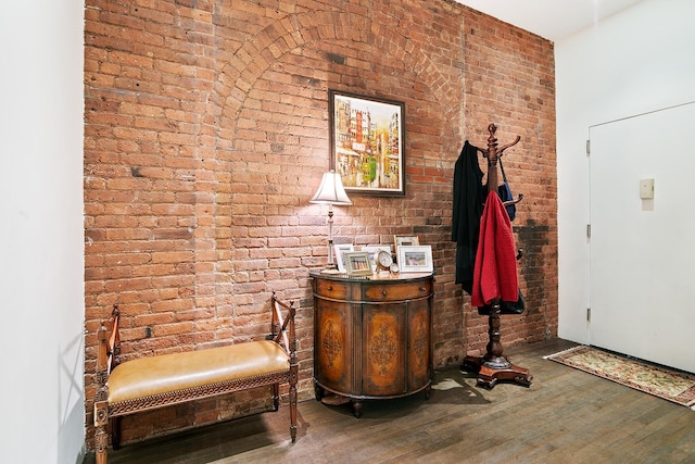 foyer featuring wood finished floors and brick wall