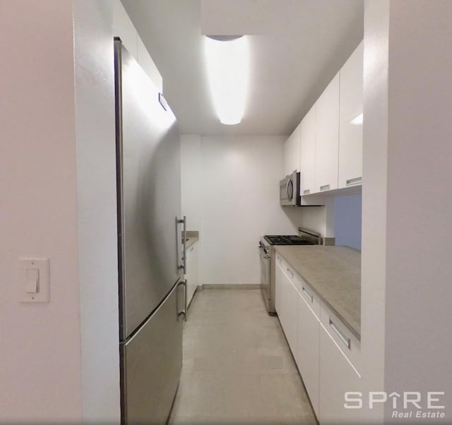 99 John St Unit 1012, New York City, NY 10038 - kitchen featuring appliances with stainless steel finishes, white cabinetry, light countertops, baseboards, and modern cabinets