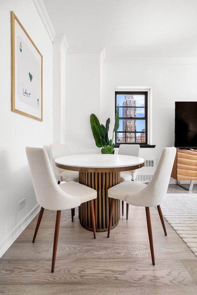 dining area featuring baseboards, ornamental molding, and light wood-style flooring