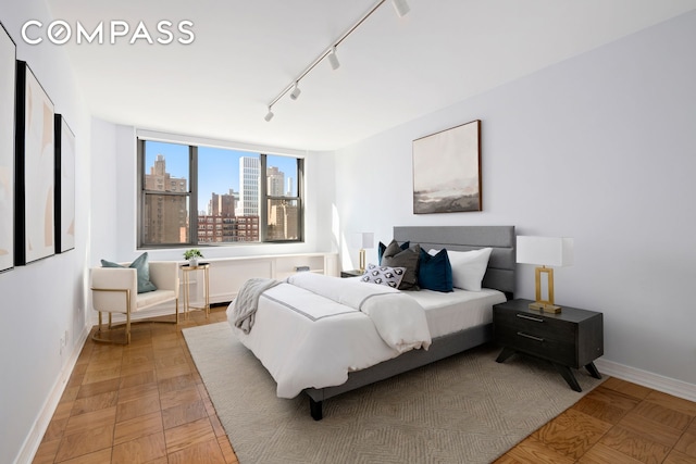 bedroom with baseboards, a city view, and rail lighting