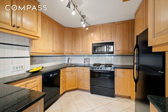 kitchen featuring light tile patterned floors, dark stone counters, a sink, decorative backsplash, and black appliances