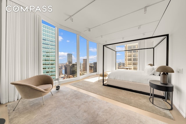 bedroom featuring track lighting, floor to ceiling windows, and a view of city