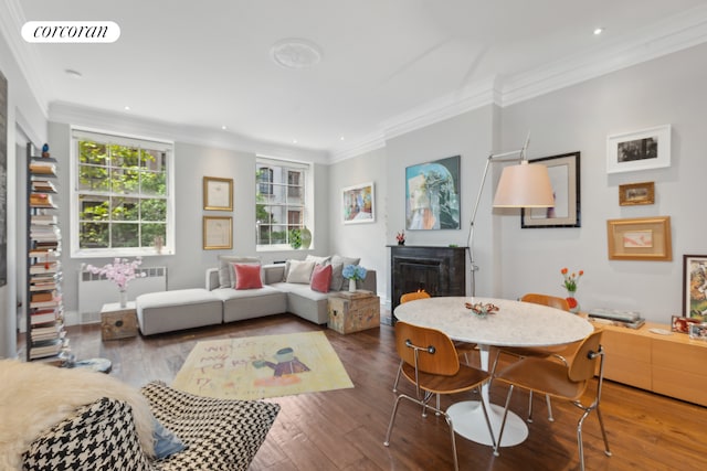 living room featuring radiator, visible vents, a fireplace, hardwood / wood-style flooring, and crown molding