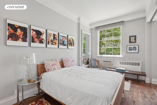 bedroom with hardwood / wood-style flooring, radiator heating unit, a wall unit AC, crown molding, and baseboards