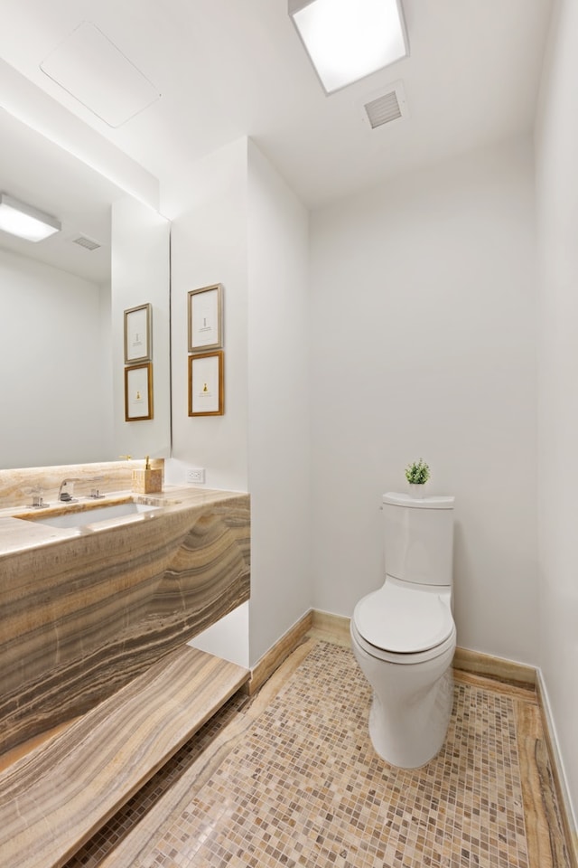 half bathroom with visible vents, baseboards, toilet, tile patterned floors, and vanity