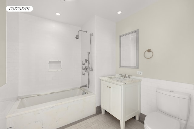 full bath featuring visible vents, tile walls, washtub / shower combination, toilet, and vanity