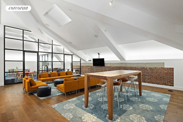 interior space with visible vents, beam ceiling, wood finished floors, and brick wall