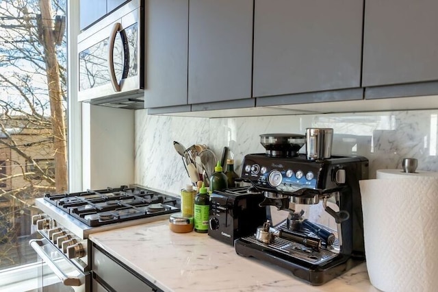 kitchen with light stone countertops, tasteful backsplash, appliances with stainless steel finishes, and gray cabinetry