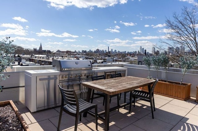 view of patio with outdoor dining space, exterior kitchen, and a view of city