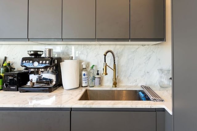 details featuring light stone counters, decorative backsplash, gray cabinets, and modern cabinets