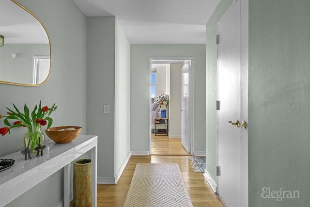 hall with light wood-type flooring and baseboards