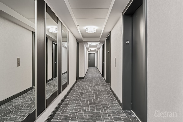 corridor featuring baseboards, elevator, and brick patterned floor