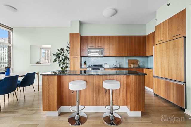 kitchen with a kitchen breakfast bar, backsplash, appliances with stainless steel finishes, and a kitchen island