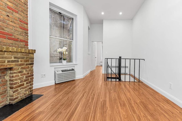 spare room with recessed lighting, baseboards, wood finished floors, and a wall mounted AC