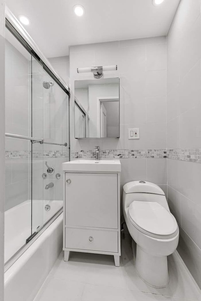 bathroom with enclosed tub / shower combo, toilet, tile walls, and vanity