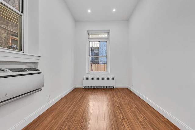 empty room with recessed lighting, radiator, baseboards, and wood finished floors