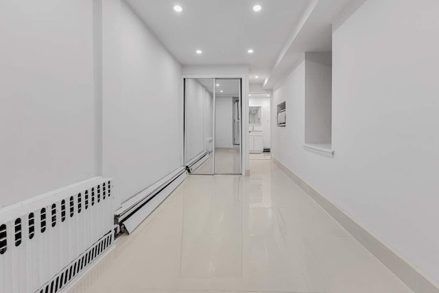 corridor with a baseboard heating unit, recessed lighting, radiator, light tile patterned floors, and a baseboard radiator