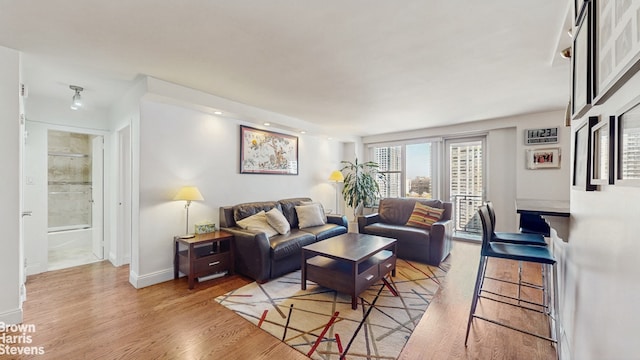 living area featuring baseboards and light wood finished floors