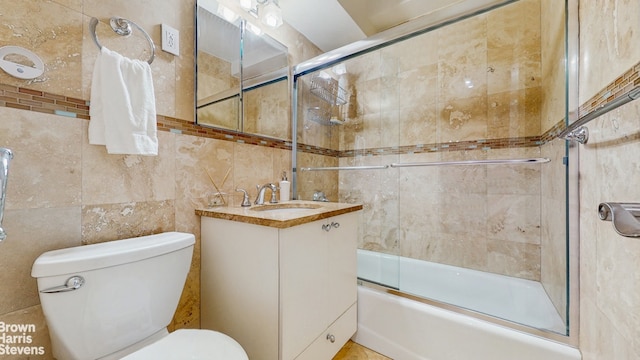 full bath with toilet, vanity, and bath / shower combo with glass door