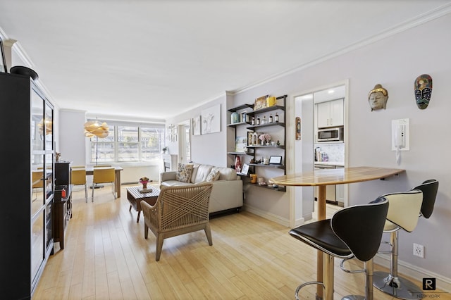 living room featuring light wood-type flooring, baseboards, and crown molding